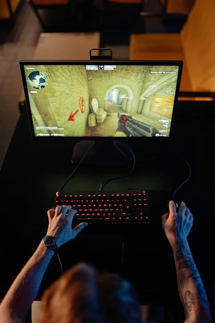 Top view of a gamer playing a video game on a computer with glowing keyboard.